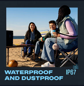 Three friends enjoying music at the beach with a heavy duty waterproof Bluetooth speaker, illustrating fun and durability.